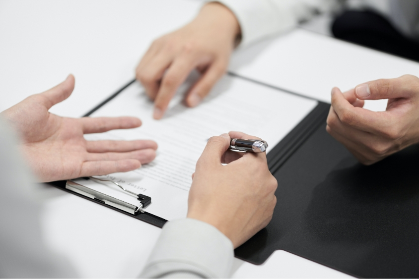 スタッフから説明を受けながら契約書を作成するイメージ写真